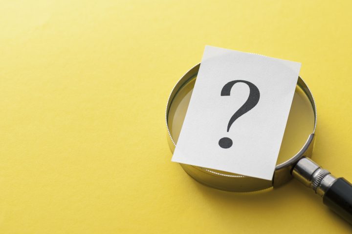 Printed question mark covering a magnifying glass